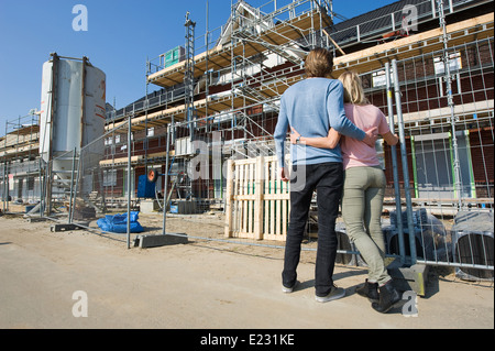 Junges Paar sucht in neu gebauten Häusern auf Baumaschinen Stockfoto