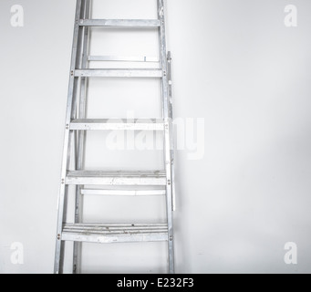 Eine Reihe von Aluminium-Schritten gegen eine weiße Wand Stockfoto