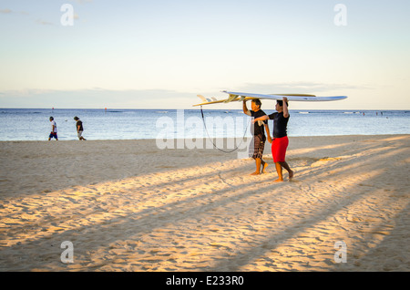 Surfer tragen ihre Surfbretter entlang Waikiki Beach in Hawaii Stockfoto