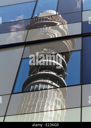 Telekom-Turm vor blauem Himmel mit weißen Wolken und Bäume verzerrte im Fenster Spiegelungen auf kubistische Weise Stockfoto
