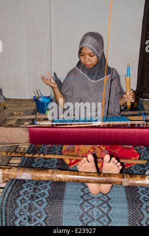 Indonesien, Insel Lombok, Sukarare. Berühmte Handwerksdorf bekannt für qualitativ hochwertige handgewebte Textilien. Junge weibliche Weberin. Stockfoto