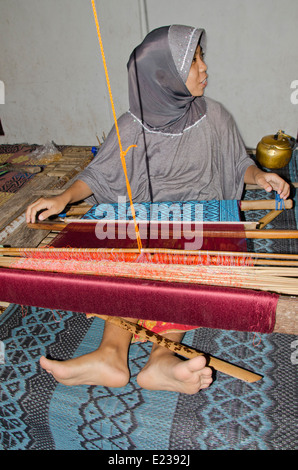 Indonesien, Insel Lombok, Sukarare. Berühmte Handwerksdorf bekannt für qualitativ hochwertige handgewebte Textilien. Junge weibliche Weberin. Stockfoto