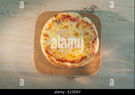 Pizza auf einem hölzernen Teller serviert. Margherita mit Tomaten-Mozzarella-Käse und Basilikum. Stockfoto