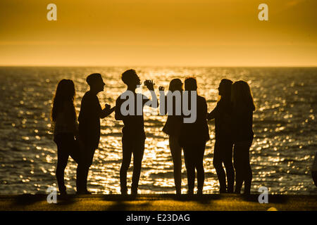 Aberystwyth Wales UK, 14. Juni 2014 am Ende von einem feinen Sommertag der fast ununterbrochenen Sonnenschein und Temperaturen um die 20 Grad Celsius, eine Gruppe von Jugendlichen treffen bei Sonnenuntergang an der Strandpromenade in Aberystwyth an der Westküste Wales, UK Photo Credit: Keith Morris/Alamy Live-Nachrichten Stockfoto