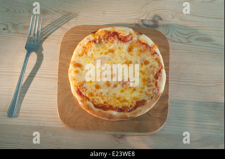 Pizza auf einem hölzernen Teller serviert. Margherita mit Tomaten-Mozzarella-Käse und Basilikum. Stockfoto