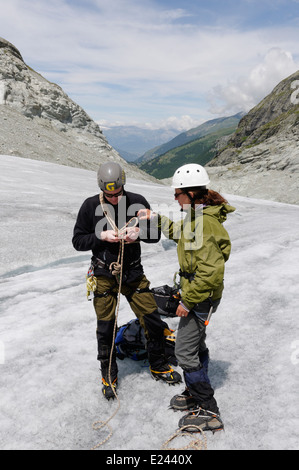 Eine Dame Bergsteiger üben binden Knoten in einem Kletterseil auf einem alpinen Kletterkurs am Ferpecle Gletscher, Schweizer Alpen Stockfoto