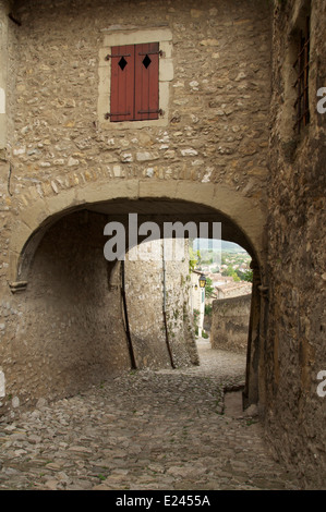 Eine schmale gepflasterte Gasse, Rue St François, führt nach unten aus dem Tour-de-Kamm in die Altstadt, Unterquerung einer mittelalterlichen Torbogen. La Drôme, Frankreich. Stockfoto