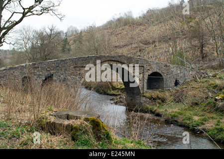 Eine alte, verfallene steinerne Brücke, die jetzt restauriert wurde, über einem Bach oder verbrennen. Stockfoto