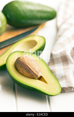 halbierte Avocados auf weißer Holztisch Stockfoto