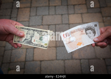 Menschen, die Austausch einer $10-Dollar-Rechnung für ein £10-Pfund-Note. Stockfoto