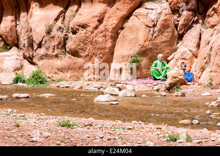 Ansicht einer Berber-Frau neben dem Wadi Tordra, der durch die dramatische Tordra Schlucht in der Nähe von Tinghir im Süden Marokkos fließt. Stockfoto