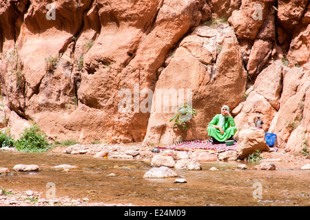 Ansicht einer Berber-Frau neben dem Wadi Tordra, der durch die dramatische Tordra Schlucht in der Nähe von Tinghir im Süden Marokkos fließt. Stockfoto