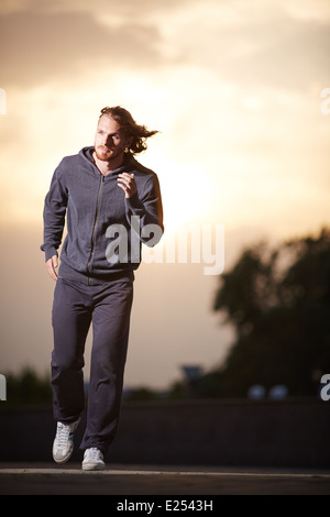 Porträt der jungen Sportler laufen am Abend Stockfoto