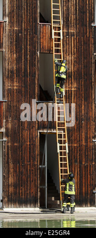 zwei Feuerwehrleute große Zugangsleiter während einer Übung in der Feuerwache Stockfoto