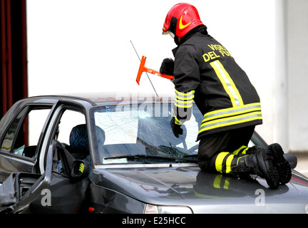 Feuerwehrchef bricht die Windschutzscheibe des Autos mit einem speziellen hammer Stockfoto