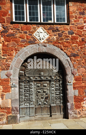 Eine geschnitzte gewölbten hölzernen Tür-Set in einer roten Mauer. Stockfoto