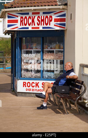 Mann sitzt auf der Bank, genießen Sie die Sonne außerhalb der Rock Shop am Ende des Bournemouth Pier. Bildnachweis: Carolyn Jenkins/Alamy Live-Nachrichten Stockfoto