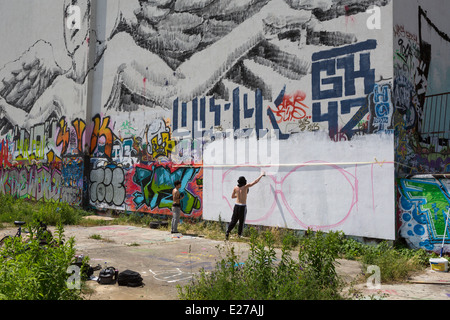 Junge Hausbesetzer Sprühen von Graffiti auf eine Mauer in Friedrichshain, einem Teil von Berlin, Deutschland Stockfoto