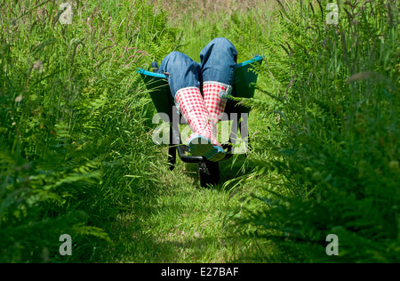 Weibliche Gärtnerin liegt in Garten Schubkarre Stockfoto