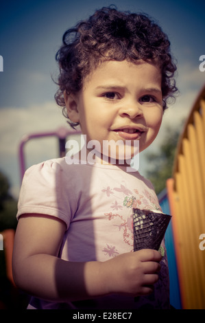 Kleinkind (2-3) auf Spielplatz beim Essen ein Eis Stockfoto