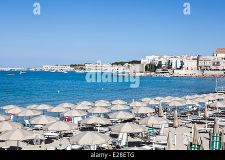 Strand-Sonnenschirme an einem sonnigen Strand im Sonnenschein im Sommer an der Küste von Otranto, Apulien, Salento Region des südlichen Italien Stockfoto