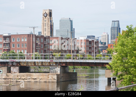 eine Eisenbahnbrücke überquert die Lachine Canal in Montreal, mit der Innenstadt und der Atwater Market im Hintergrund Stockfoto