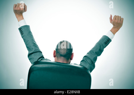 ein Geschäftsmann erstreckt sich unter dem Vorsitz seines Amtes Stockfoto