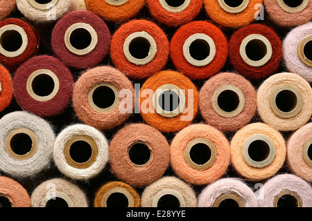 eine große Sammlung von Orange und andere bunte Vintage Handwerk Garn Spulen gesammelt als Hintergrund. Stockfoto