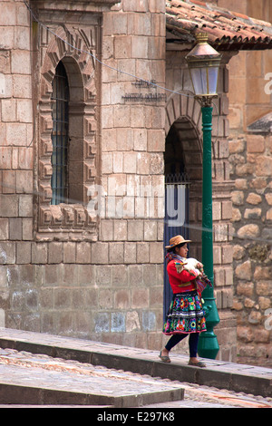 Ein Mädchen geht, hält ein Lamm in Cusco, Peru, dem alten Sitz des Inka-Reiches hoch in den Anden. Stockfoto