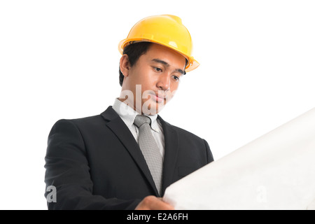 Nahaufnahme einer asiatischen jungen Mannes trägt einen Bauarbeiterhelm betrachten Blaupause Papier isolierten auf weißen Hintergrund stehen. Stockfoto