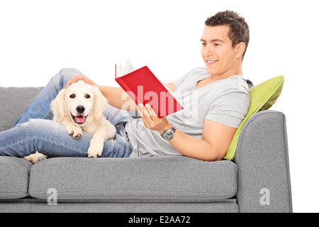 Mann auf Sofa mit einem Welpen neben ihm liegenden Lesebuch Stockfoto