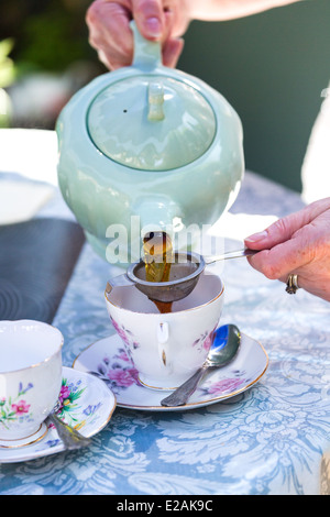 Genießen Sie Nachmittagstee. Frau gießen Tasse Tee in Ludham Dorf Teestube. Norfolk Broads England Großbritannien Stockfoto