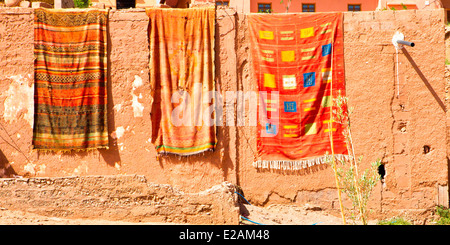 Bunte Teppiche hängen über traditionelle Ocker Pise Wände bei Ait Benhaddou in der Nähe von Ouarzazate im südlichen, Marokko, Nordafrika. Stockfoto