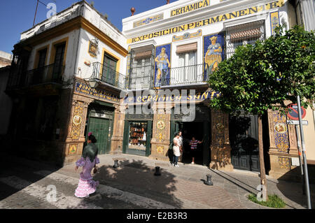 Spanien, Andalusien, Sevilla, Triana, Frau trägt eine Kleid Gipsy auf der Straße, ein Geschäft Azulejos im Hintergrund Stockfoto