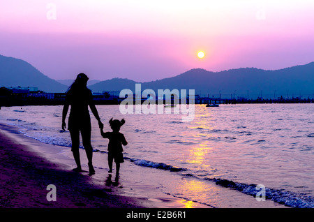 Silhouette von Mutter und Kind zu Fuß auf Sonnenuntergang Stockfoto