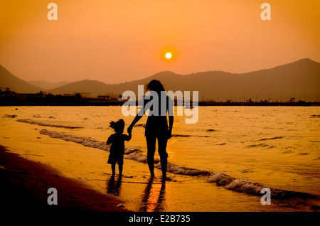 Silhouette von Mutter und Kind zu Fuß auf Sonnenuntergang Stockfoto