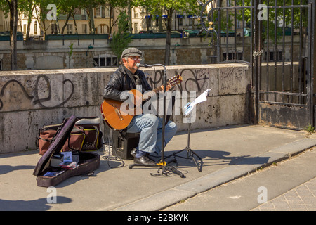 PARIS - 3. Mai: Busker singt französische Chansons mit einer Gitarre an der Küste in der Nähe von Notre Dame in Paris am 3. Mai 2014. Stockfoto