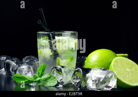 Mojito cocktail mit frischen Limetten, Minze und Eis Würfel am schwarzen Tisch Stockfoto