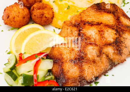 Gegrillter Lachs mit Käse Kartoffelpüree, Gemüse und Hush Welpen. Stockfoto