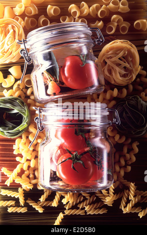 Zwei Kilner Gläser mit Tomaten, Knoblauch und Kräutern, auf einem Hintergrund von verschiedene Pasta, Pasta-Saucen zu vertreten. Stockfoto