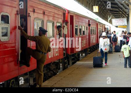 Central Province, Nuwaraelyia Bezirk, Nanu Oya, Sri Lanka, Railway station, geht und kommt von Reisenden auf einer Kai Plattform vor rote Autos Stockfoto