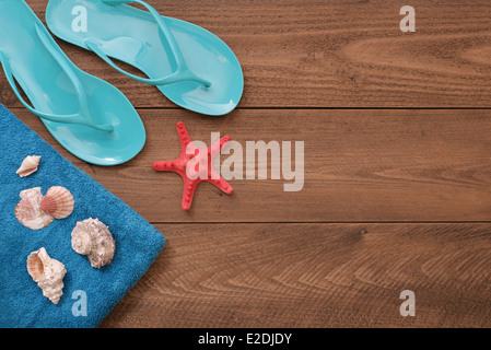 Blaue Flip-flops mit roten Seesternen und Handtuch auf hölzernen Hintergrund, Ansicht von oben Stockfoto
