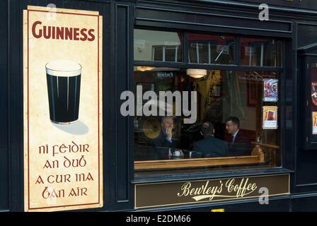 Irland Galway County Galway Fassade von einer Kneipe Männer in Anzügen in Guinness gälische gemalte Werbung Stockfoto