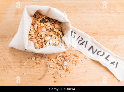 Müsli in einem cremefarbenen Stoffbeutel mit einem Etikett auf einem Holzbrett (12 von 15) Stockfoto