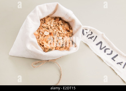 Müsli in einem cremefarbenen Stoffbeutel mit einem Etikett auf einem blassen Grün Brett (13 von 15) Stockfoto