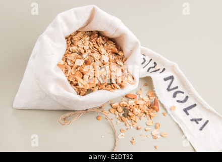 Müsli in einem cremefarbenen Stoffbeutel mit einem Etikett auf einem blassen Grün Brett (14 von 15) Stockfoto