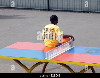 Junge sitzt auf einer Tischtennisplatte Stockfoto