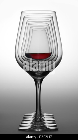 einige Gläser Wein im Farbverlauf grau zurück in der Folge in einer Reihe stehen, eine teilweise mit Rotwein gefüllt Stockfoto