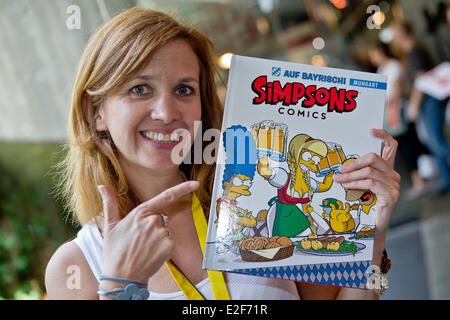 Erlangen, Deutschland. 19. Juni 2014. Die Synchronsprecherin von 'Lisa' der Cartoon-Serie "The Simpsons", Sabine Bohlmann, zeigt bayerische Versionen von "The Simposns" Comic-Bücher während des 16. Internationalen Comic-Salon-Festival in Erlangen, Deutschland, 19. Juni 2014. Bohlman übersetzt Comics in bayerischen Dialekt. Das größte Comic-Festival für die deutschsprachigen Märkte läuft bis 22 Juni. Foto: DANIEL KARMANN/Dpa/Alamy Live News Stockfoto