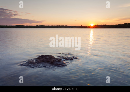 Die untergehende Sonne über einen Felsen, der kaum über dem Wasser in Georgian Bay sitzt. Massasauga PP, Ontario, Kanada. Stockfoto